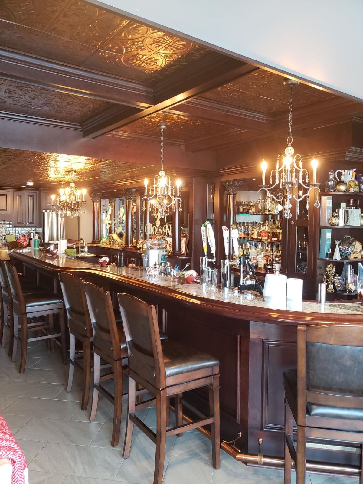 The mahogany bar and back shelves under the chandelier
